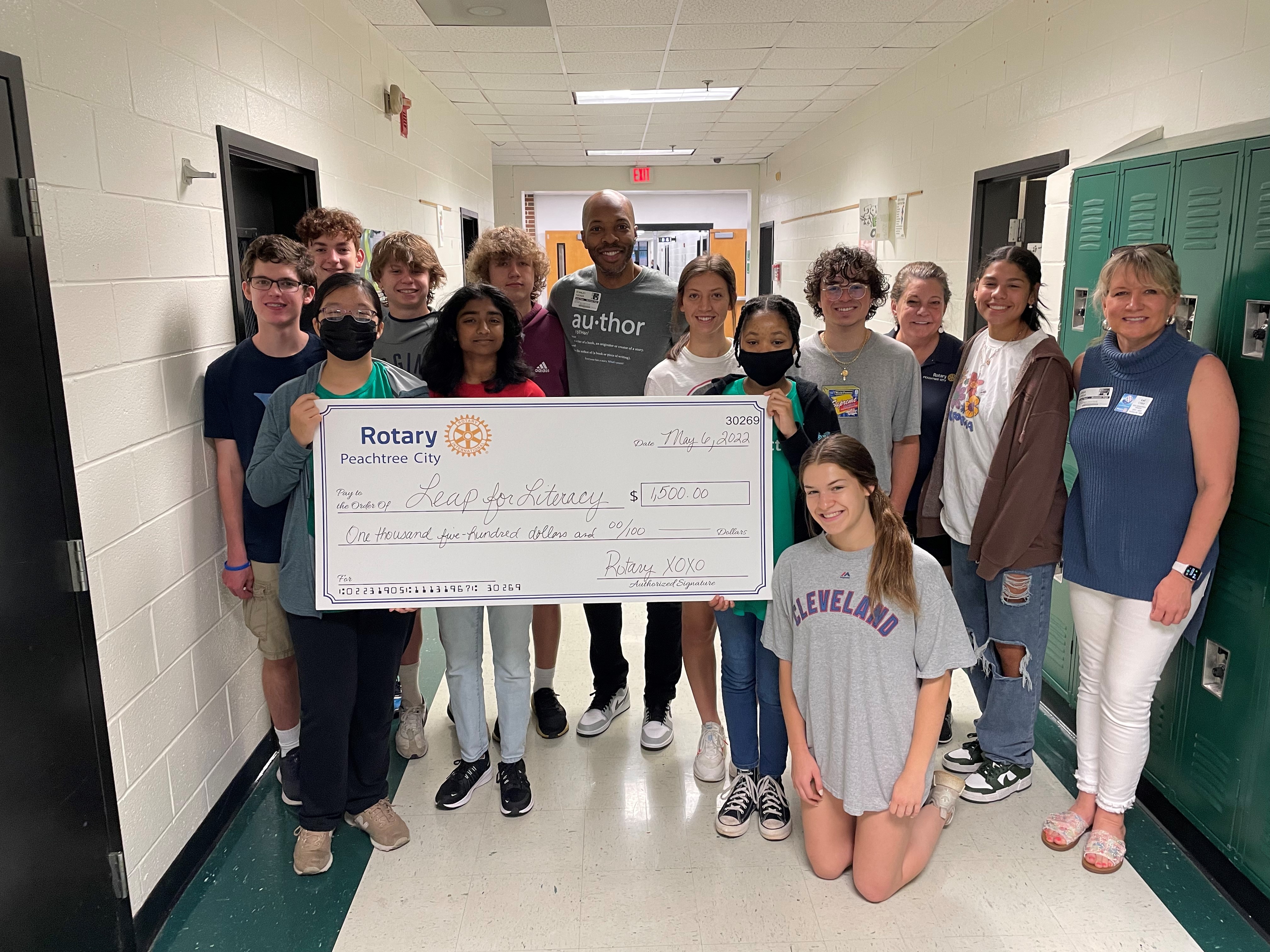 Lei Lydle, as Director of New Generations for the Peachtree City Rotary Club, along with the McIntosh High School Interact Club presenting a $1,500 donation check to Leap for Literacy.